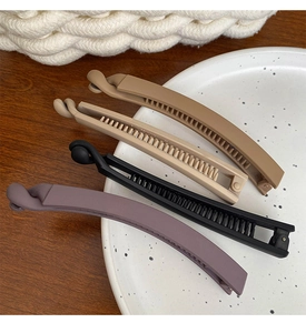Close-up of four matte banana clips in coffee, beige, black, and purple on a white plate