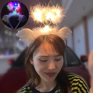 Close-up of LED glowing angel wing headband with white feathers and warm yellow light