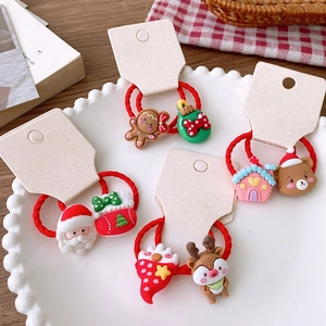 Detail of red Christmas hair elastics with festive charms on white display card