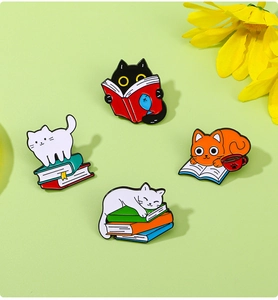 Detailed macro shot of four colorful cat enamel pins featuring books and coffee designs