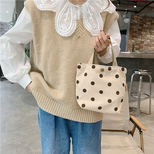 Detailed close-up of corduroy tote bag in beige with brown polka dots and metal buckle