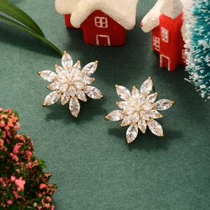 Close-up of golden snowflake earrings with cubic zirconia in festive holiday setting