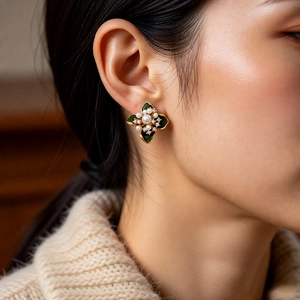 Gros plan de boucles d'oreilles fleurs vintage dorées avec émail vert et perles