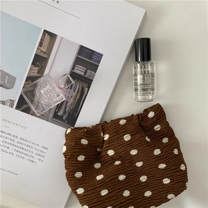 Macro shot of brown polka dot pleated chiffon cosmetic bag on minimalist background