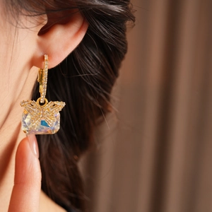 Detail eines goldenen Schmetterling-Ohrrings mit Zirkonia und großem Kristall am Model