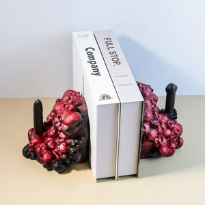 Detail view of red and black gradient skull bookends holding white books in resin finish