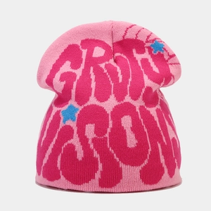 Detailed knit texture of a pink beanie with Y2K style graffiti letters and blue stars