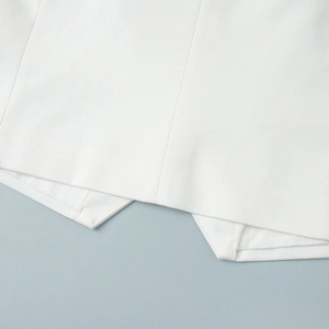 Detail of white V-neck vest showing asymmetric hemline and premium woven fabric texture
