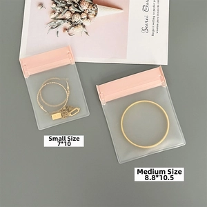 Close-up of frosted jewelry storage bags with pink zippers and golden accessories