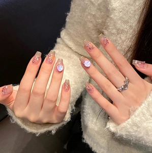 Detailed view of pink shimmer press-on nails with glitter and pearl effect on hand