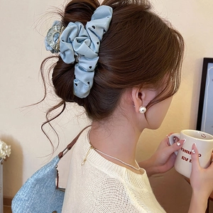 Blue chiffon hair claw clip with black heart pattern worn on a bun hairstyle