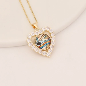 Detail of gold heart pendant with cubic zirconia and colorful Eye of Horus charm