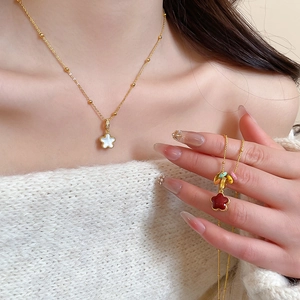 Macro shot of gold star necklaces featuring white shell and red enamel inlays