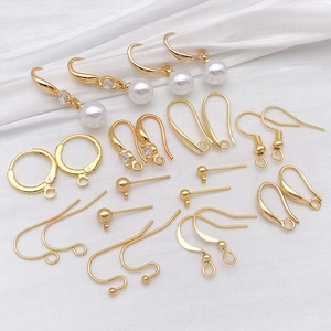 Golden DIY jewelry earring making kit with pearl and zircon charms on striped background