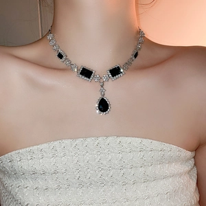 Close-up of vintage silver necklace with black gemstone and waterdrop pendant on model