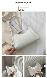 Close-up of white crocodile pattern shoulder bag with a zipper and faux leather texture