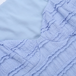 Close-up of light blue dress showing textured fabric and delicate layered lace trim