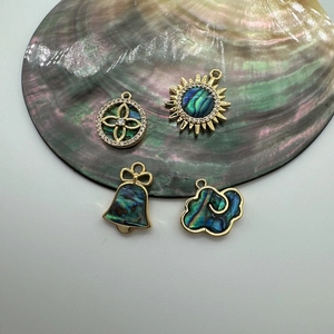 Detailed view of 18K gold plated charms with abalone shell in sun, flower, bell, and cloud shapes