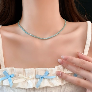 Gros plan du collier de perles bleu clair sur le cou du mannequin avec haut en dentelle