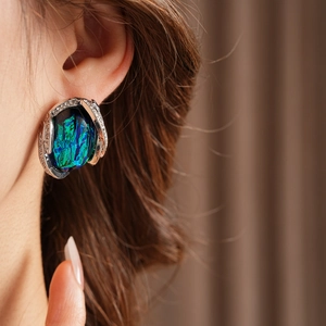 Close-up of vintage resin earring with blue-green opal stone and silver diamonds