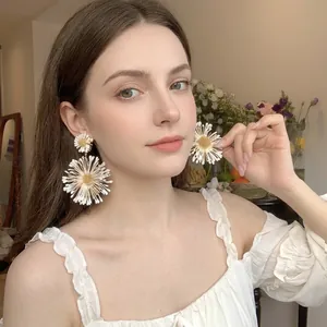 Detailed close-up of large white daisy raffia earrings on a model for beach vacation style