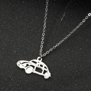 Detail view of the stainless steel car pendant necklace on a black textured background