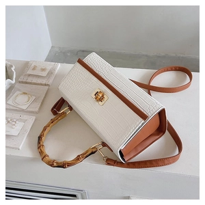 Detail of white crocodile pattern handbag featuring unique bamboo handles and gold hardware