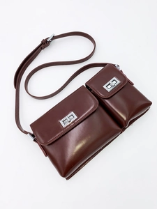 Detail of dark brown leather crossbody bag with double compartments and silver twist locks