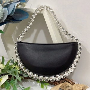 Detail view of the black crescent bag featuring large round rhinestones on the edges