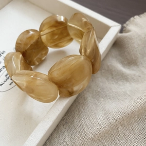 Close-up of amber resin beads with tortoiseshell texture on a minimalist cream tray
