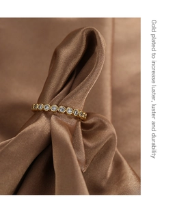 Close-up of gold plated ring with micro-inset white zircons on brown silk fabric