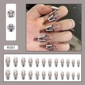 Macro view of 24pcs nude and white French press-on nails with black lace texture and gold dots