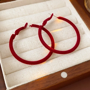Close-up of red flocked velvet hoop earrings displayed inside a wooden jewelry box