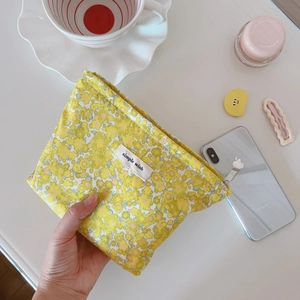 Dettaglio della piccola borsa cosmetica in cotone a fiori gialli con cerniera in argento