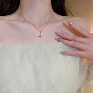 Close-up of rose gold butterfly necklace with white mother of pearl and zircon details