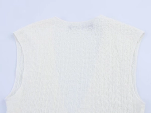 Close-up of white sleeveless top showing textured stretch pleats and ruched fabric detail