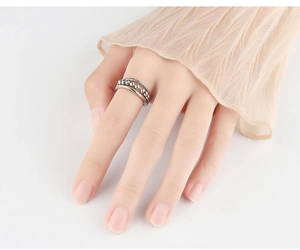 Detail of silver anti-anxiety spinner ring with beads worn on finger over beige tulle