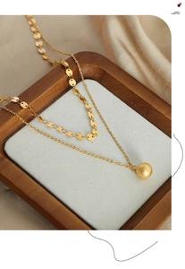 Detail of double-layer gold plated necklace with matte ball pendant and flat disc chain