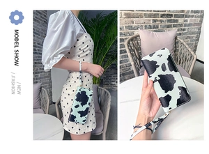 Detail of a cow print long wallet with a matching wristlet strap for fashion styling