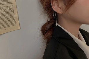 Detail of long pearl chain ear cuff in silver finish worn on the ear for a trendy look