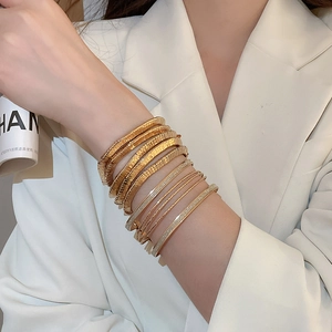 Detail of layered gold bangles featuring textured ridges and shimmering finishes