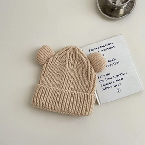 Close-up of beige knit beanie featuring thick ribbed texture and cute bear ear details