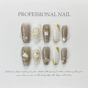 Detailed view of handmade press-on nails with gold foil, shell shards and wire accents