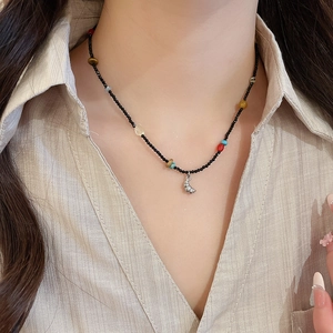 Detailed shot of ethnic beaded necklace with a silver shell pendant on a model