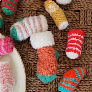 Mini knitted Christmas stockings in various striped colors on a natural rattan background