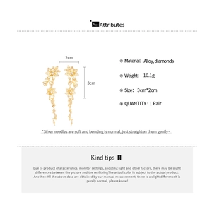 Detailed view of golden pleated flower earrings with rhinestones and silver needles