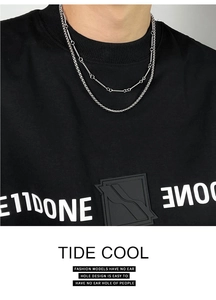 Detailed close-up of double-layered silver titanium steel necklace on a black shirt