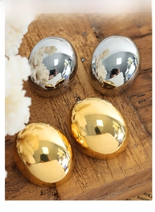 Detailed view of polished oval titanium steel earrings in glossy gold and silver finishes