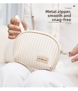 Detail of cream PU leather makeup bag with vertical quilting and metal zipper
