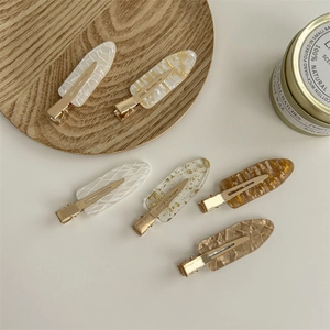 Elegant French style resin hair clips set in various marble patterns on a wooden tray